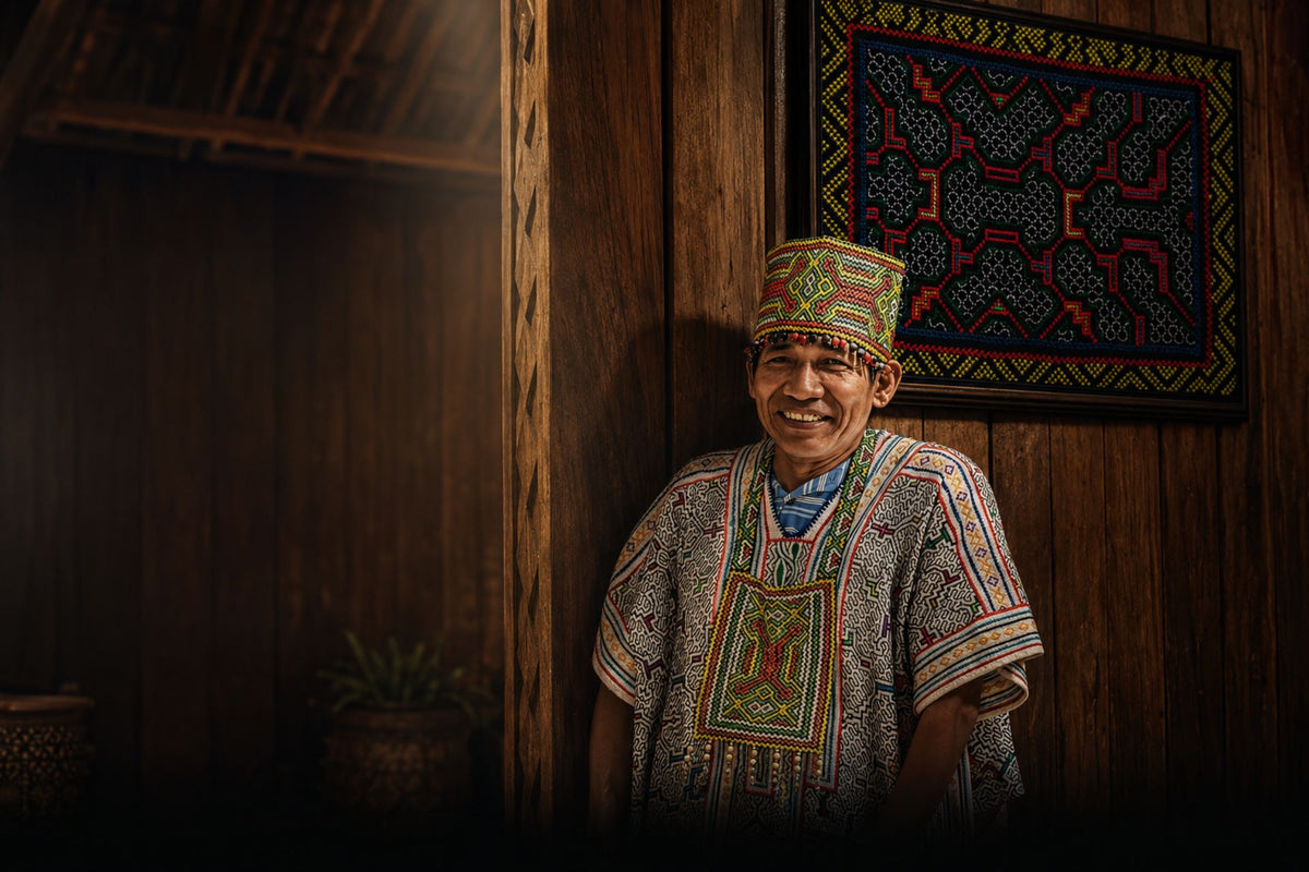 Maestro Luis Marquez Pinedo in traditional Shipibo dress in front of a Kené textile